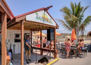 local musician providing entertainment on outdoor sage and beachfront patio