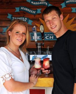 smiling young couple posing with cocktails at bar counter