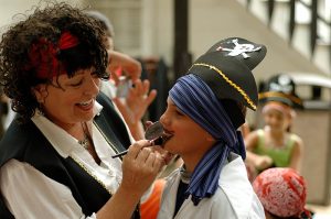 Woman helping boy with pirate outfit and makeup