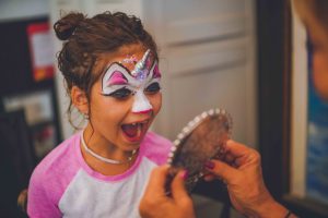 little girl seeing herself with unicorn face paint