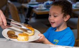 Child getting a biscuit placed on his plate for breakfast