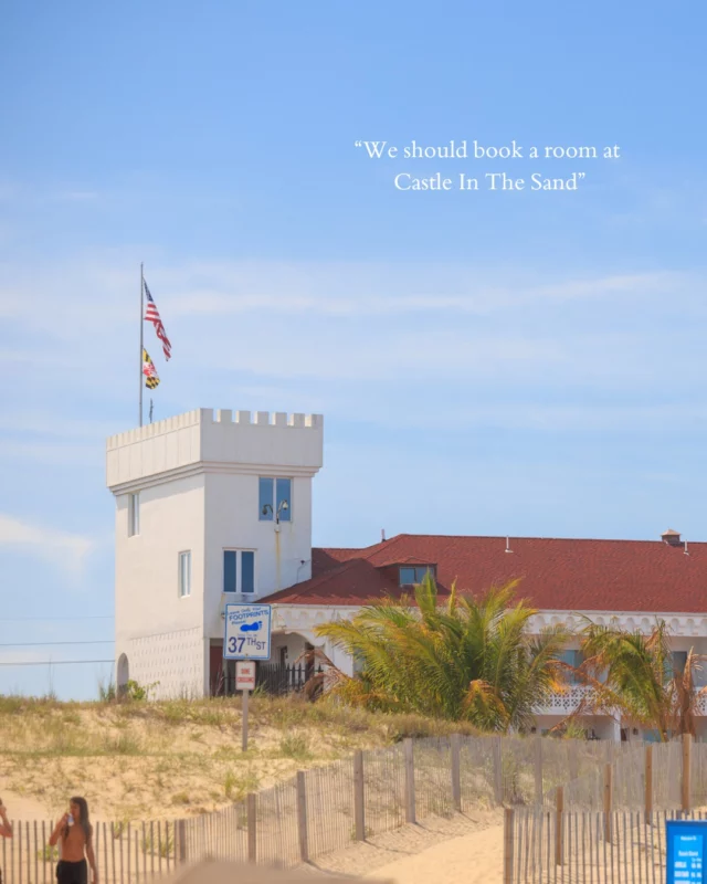 A white building with a red roof and a tower, fenced area in front of it