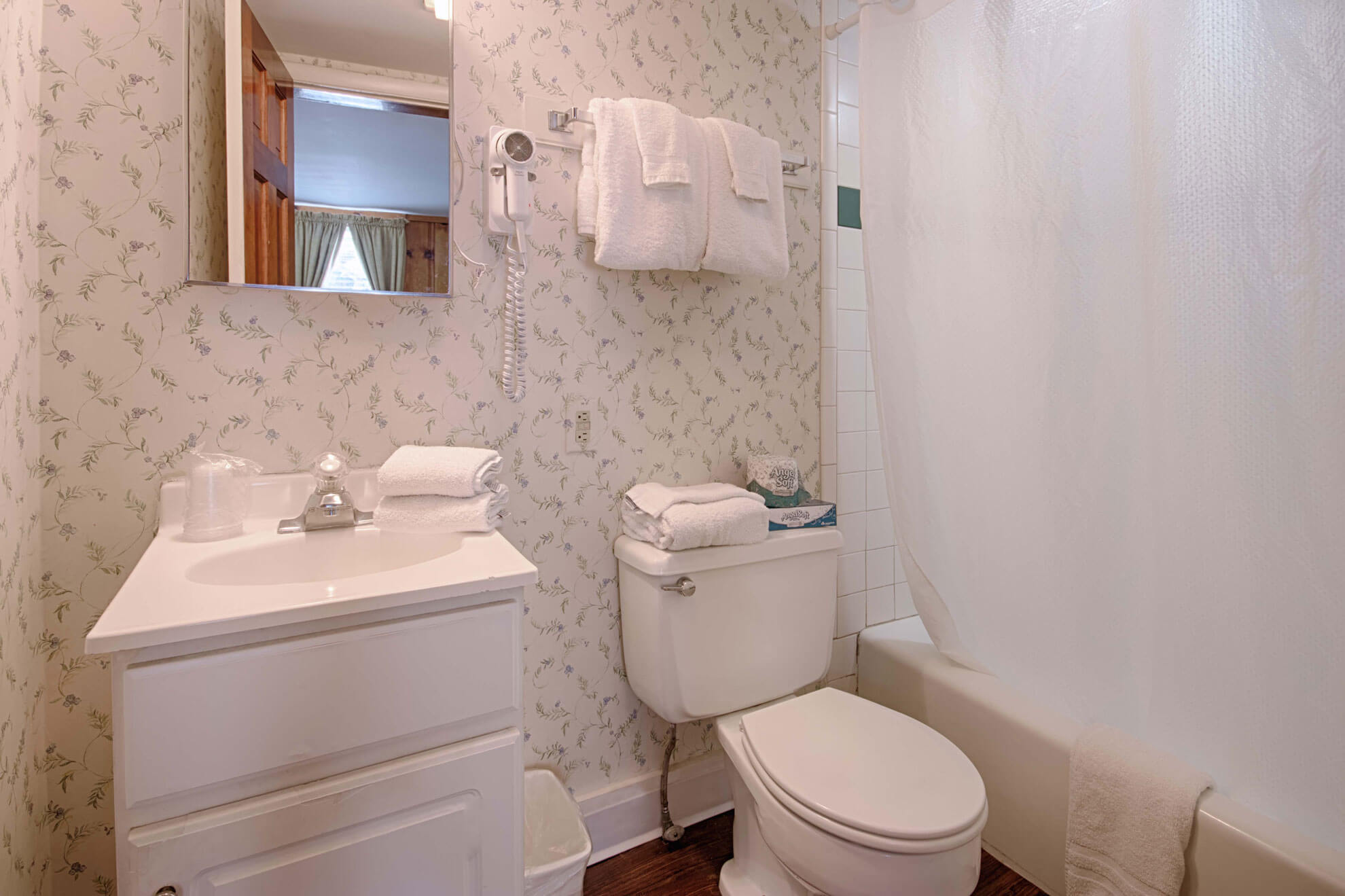 a bathroom with a toilet, sink, mirror and bathtub