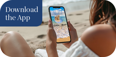 a woman sitting on the beach looking at her phone