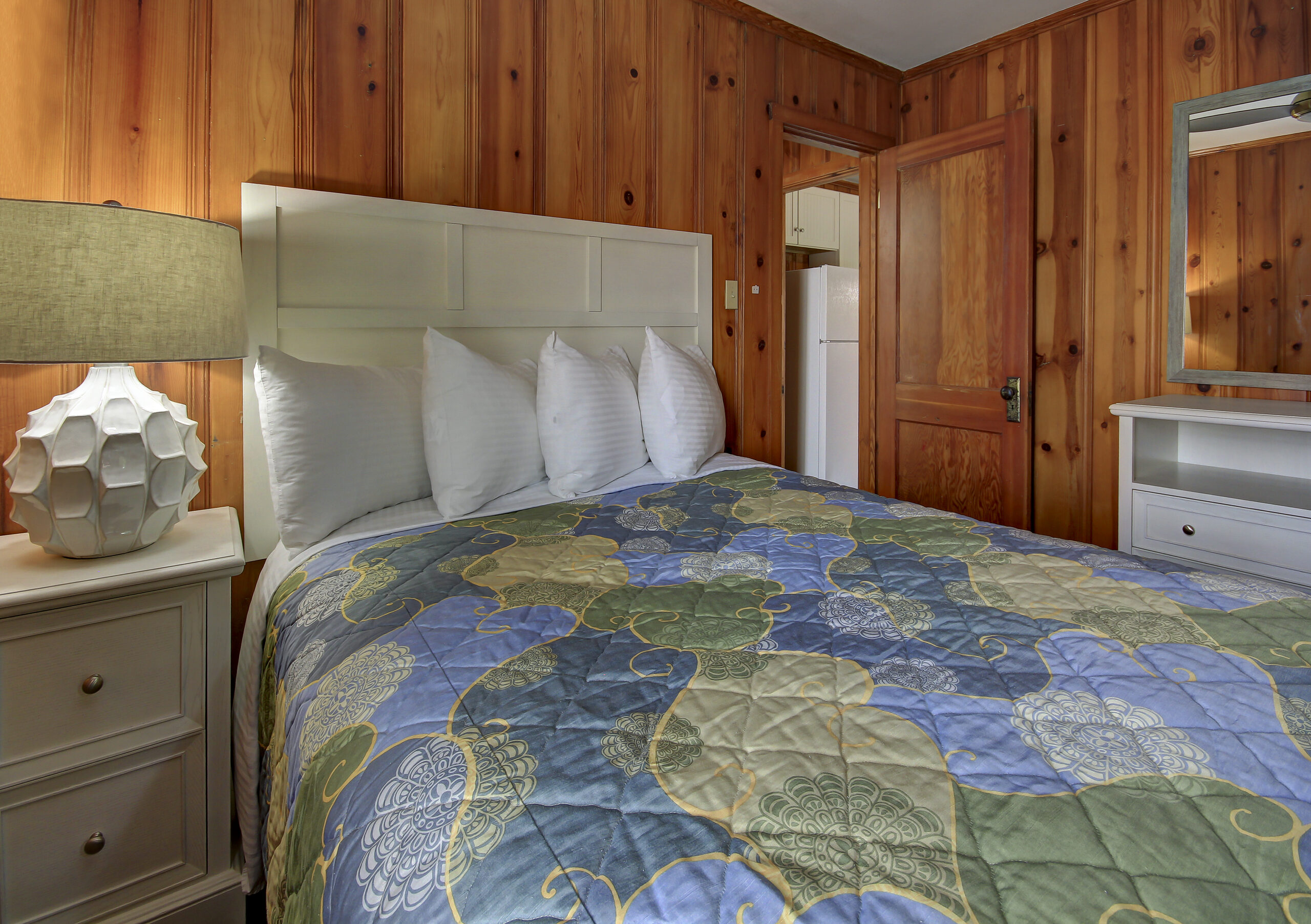 a bedroom with a bed, dresser and mirror