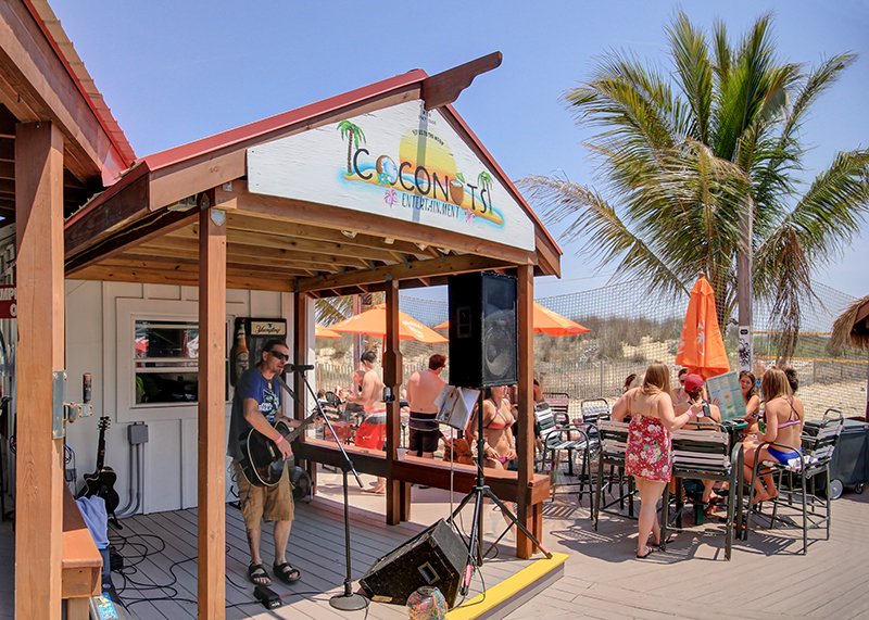 a group of people standing around a bar on a beach