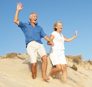 a man and a woman running up a sand dune