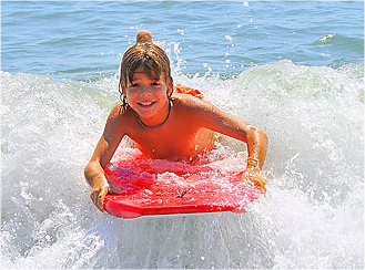 a young boy riding a red surfboard on a wave