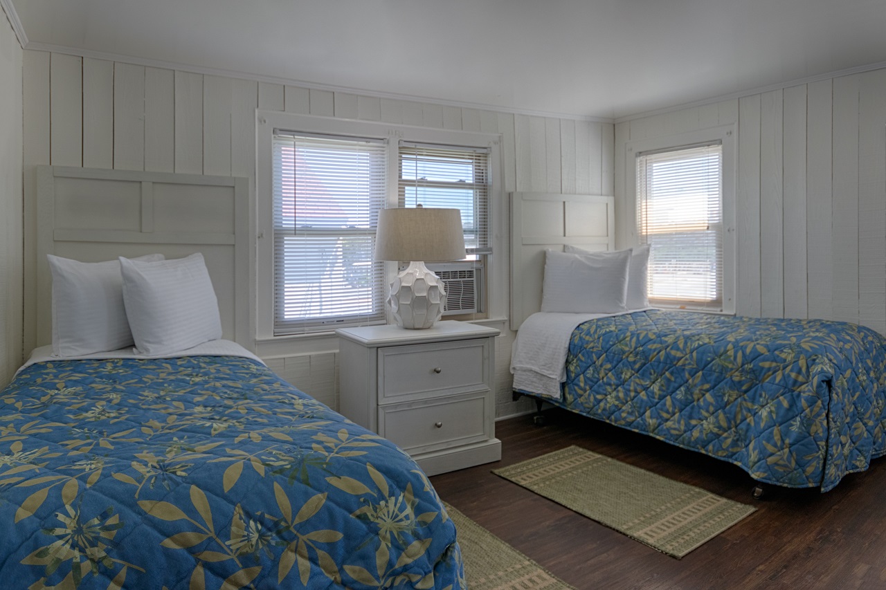 two beds in a room with white walls and wood floors