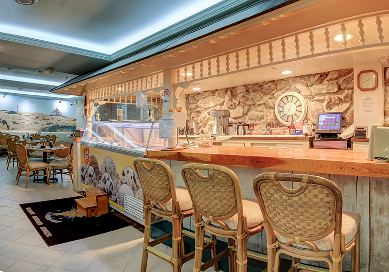 a restaurant with chairs and a bar with a clock on the wall