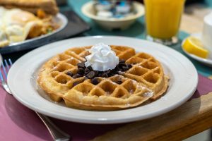 a plate of waffles with whipped cream on top