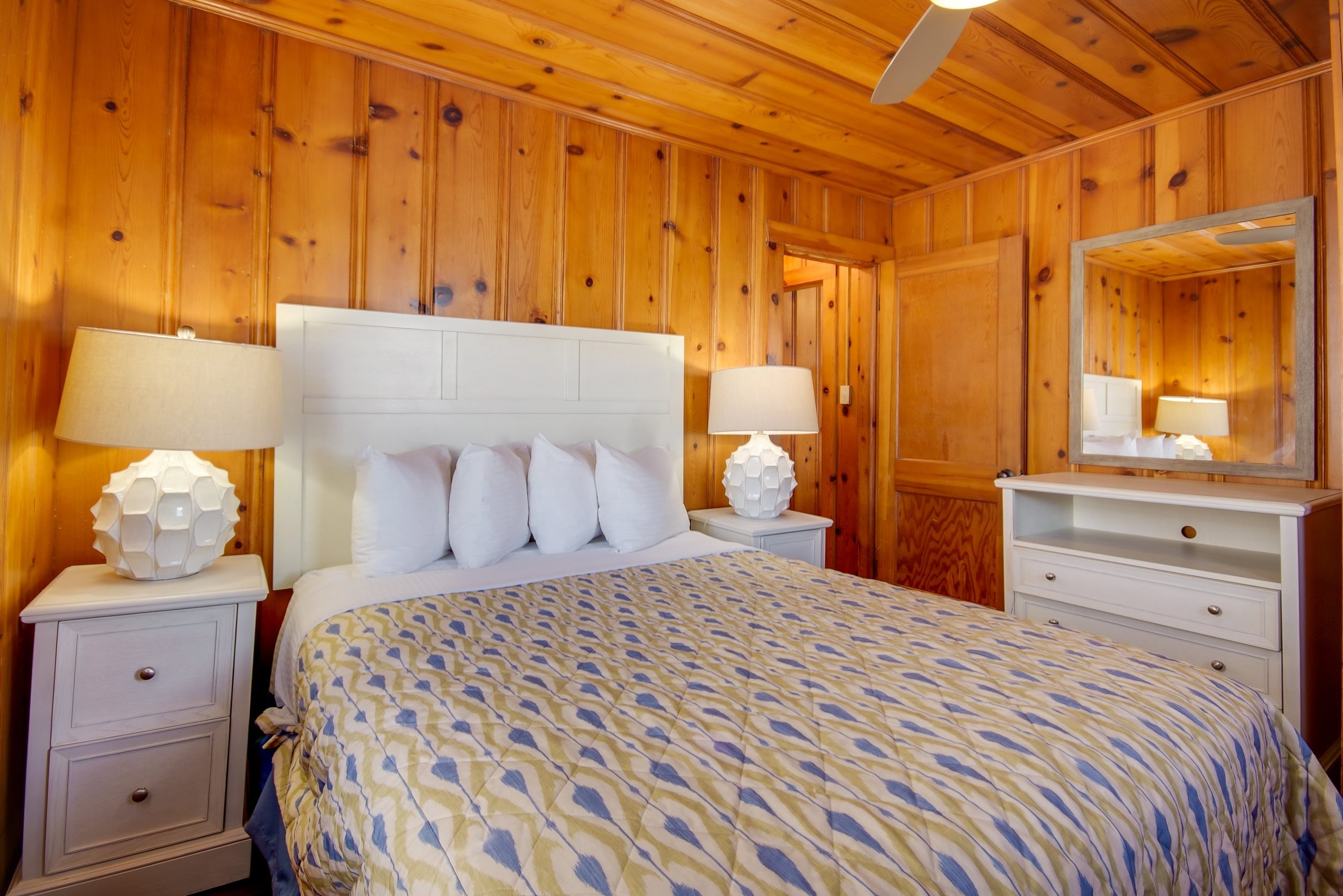 a bedroom with wood paneling and a ceiling fan