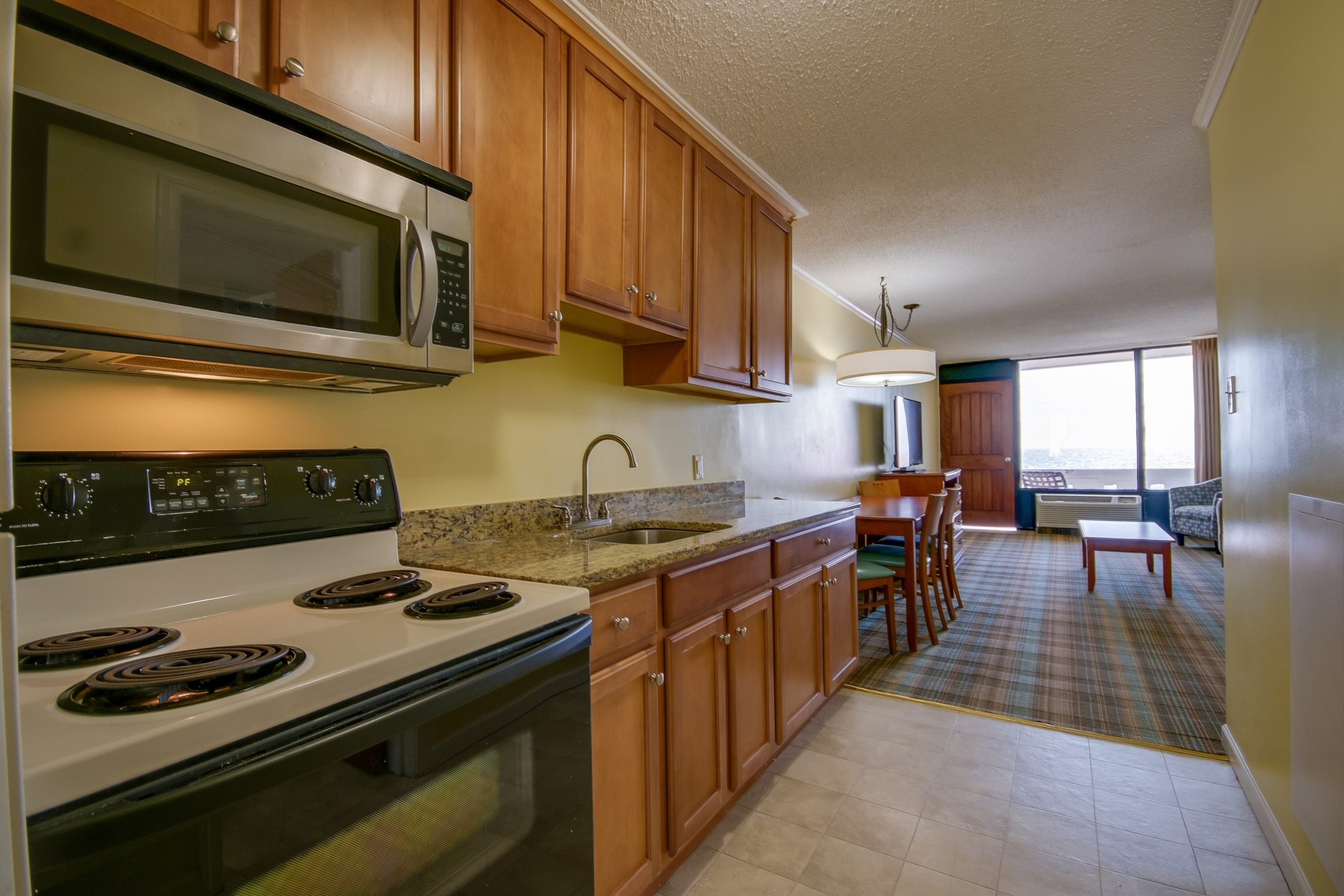 a kitchen with a stove, microwave, and dining area