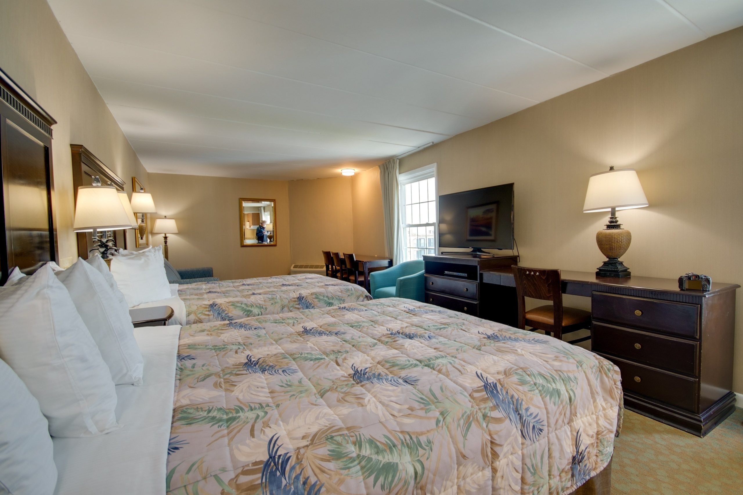 a hotel room with a bed, desk and television