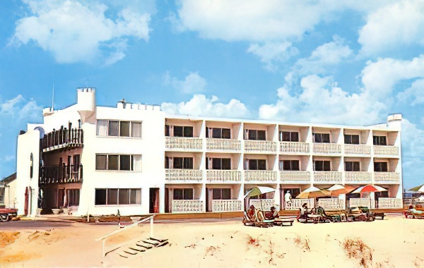 a white building on the beach with a blue sky in the background