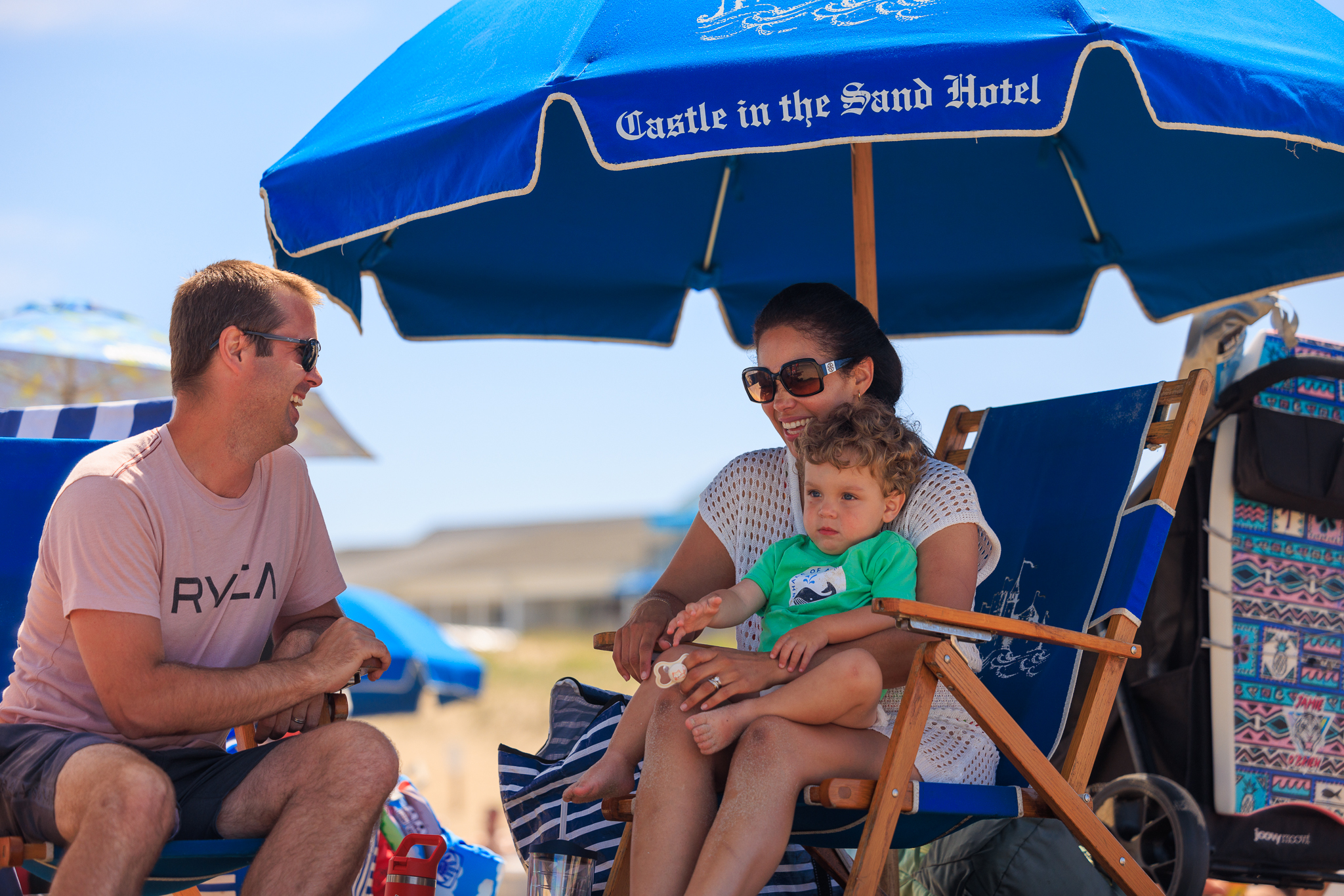 a group of people sitting under a blue umbrella