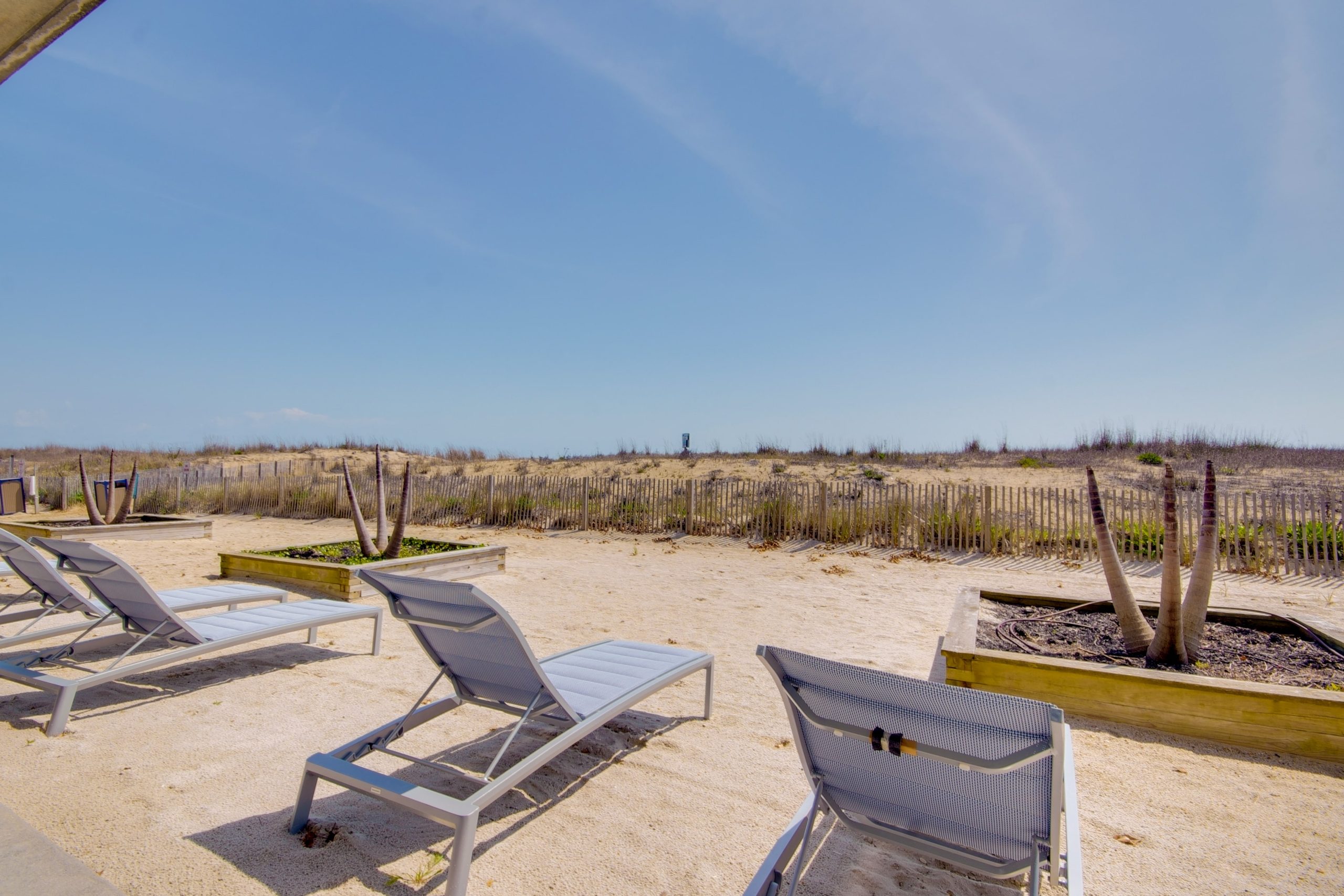 a couple of lawn chairs sitting on top of a sandy beach