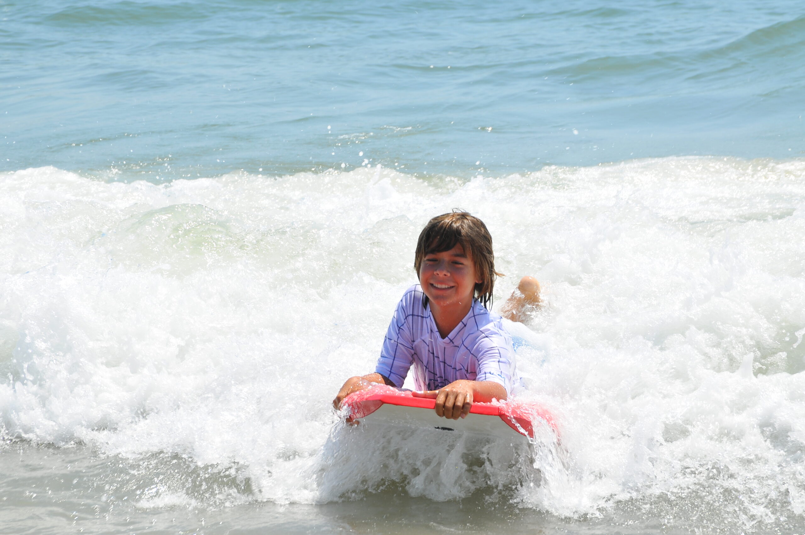 a little girl riding a boogie board in the ocean