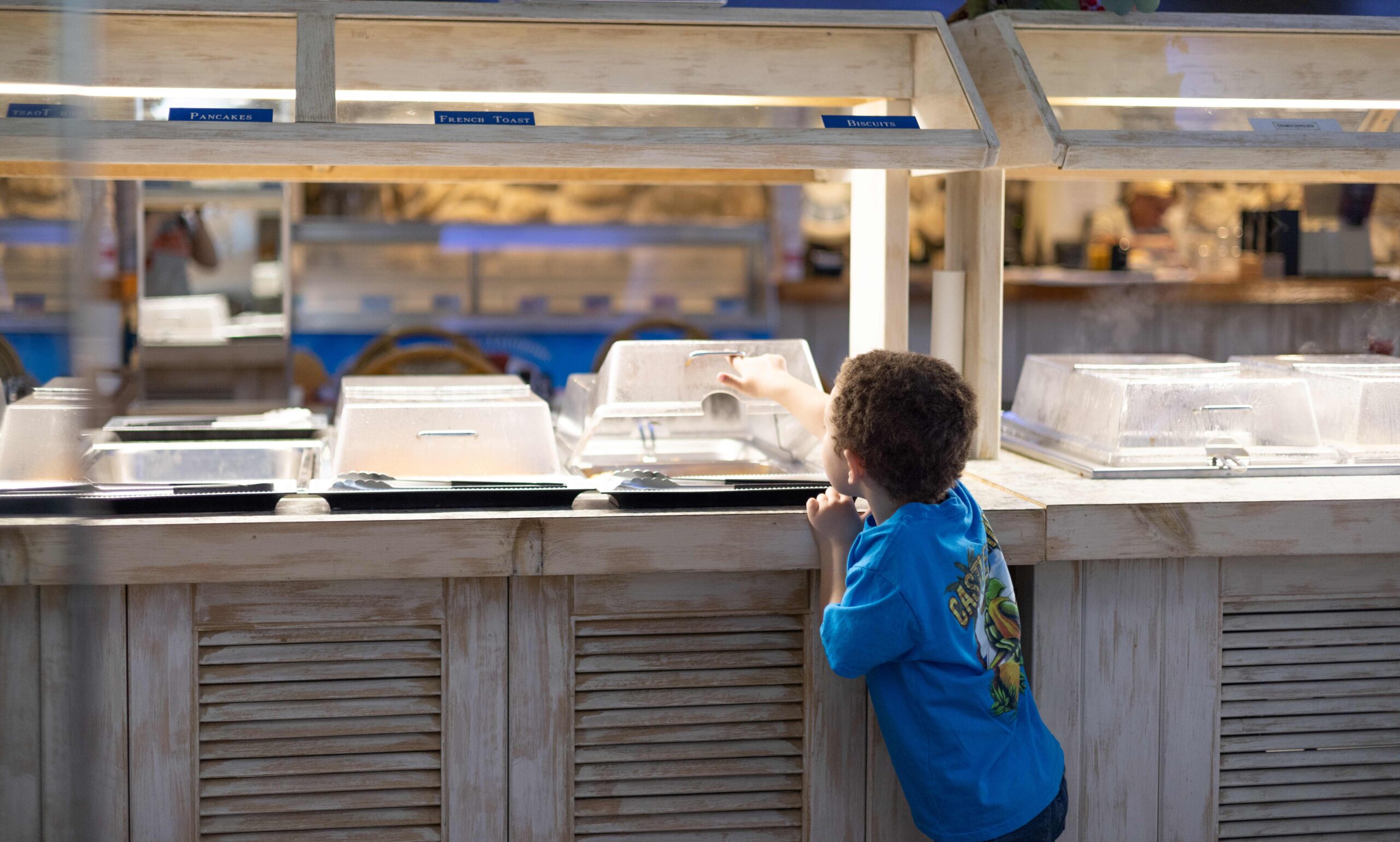 a little boy standing at a counter looking at food