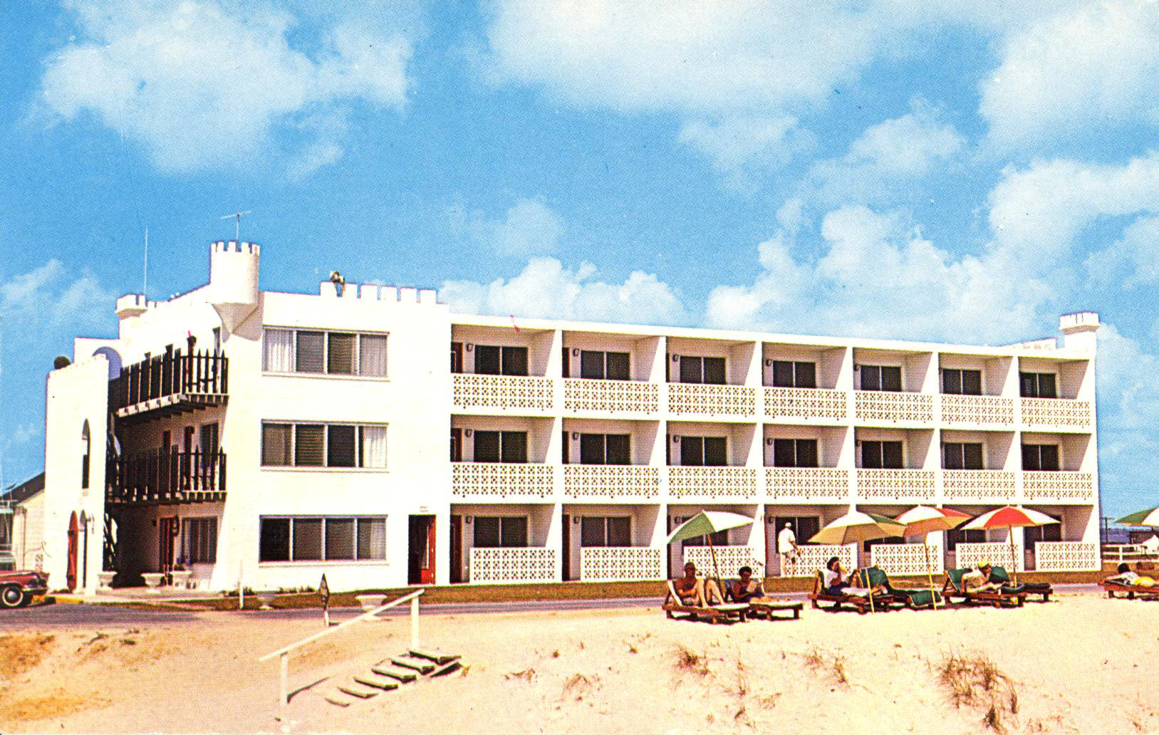 a hotel on the beach with people sitting under umbrellas